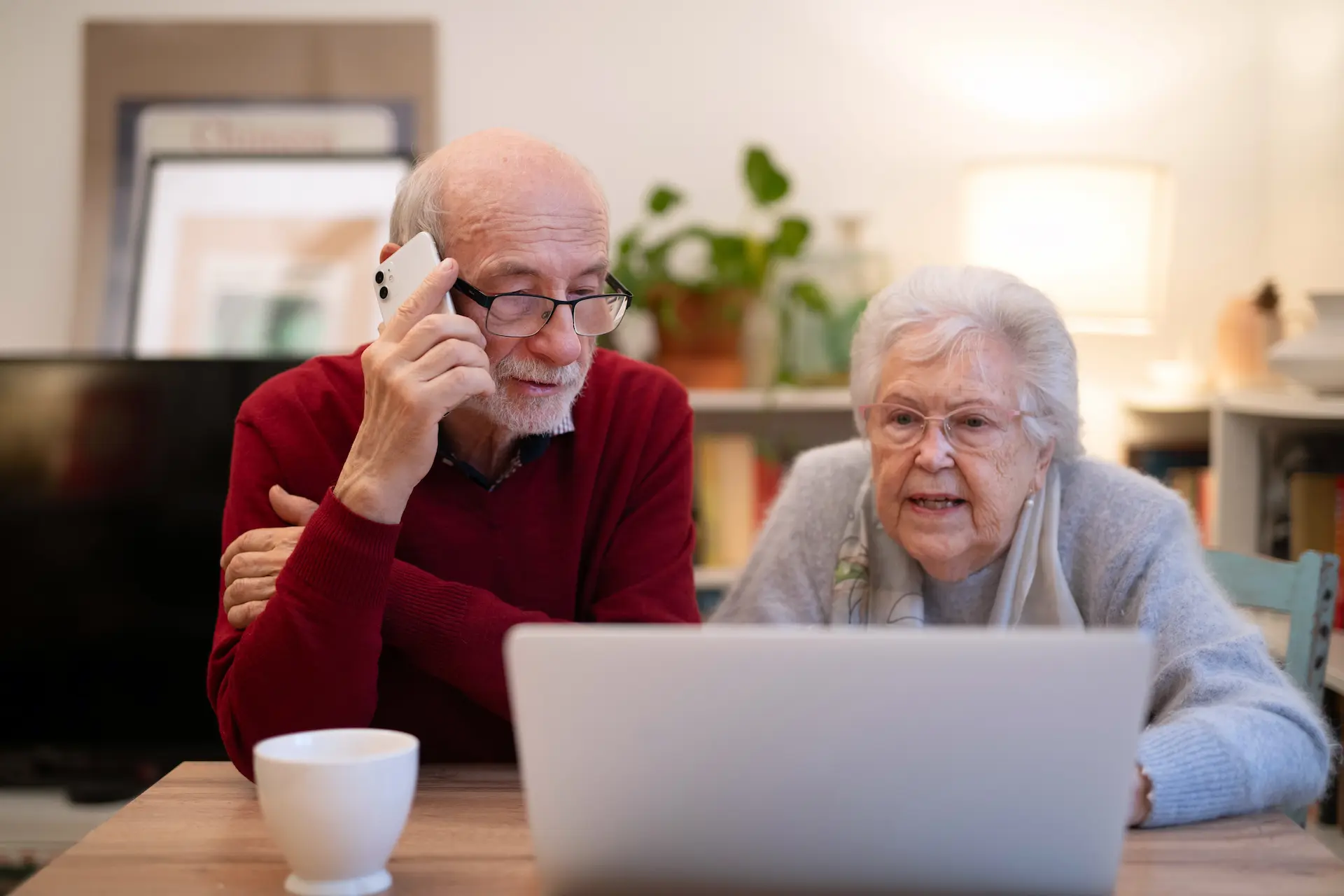 Elderly man video calling his grandchildren on a tablet with his companion's help